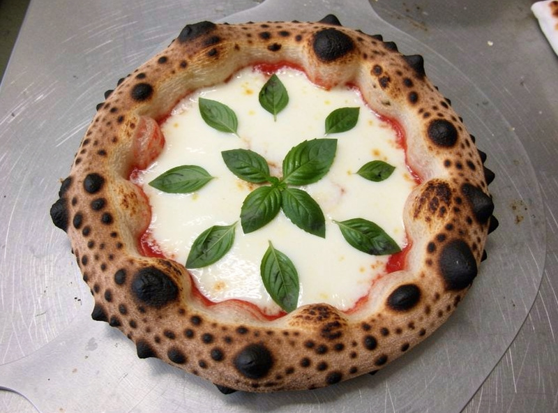 Finished Neapolitan pizza with leoparded cornicione and soft center fresh from a high temperature pizza oven