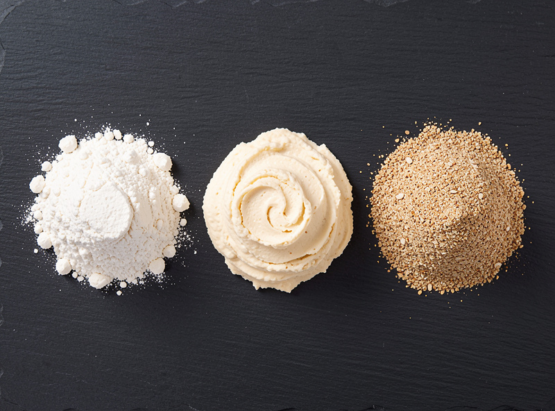 Three pizza flours side by side: refined 00, strong bread flour, and stone-ground wheat showing color and texture differences